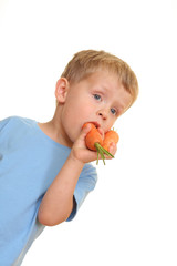 three years old boy eating fresh carrot isolated on white