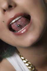 Attractive young woman sticking out her tongue to show piercing