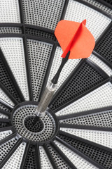 ein roter Dartpfeil trifft in das Schwarze