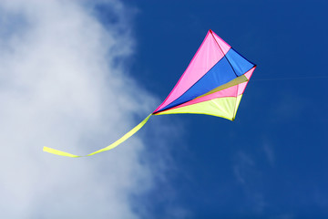 kite flying against a blue sky, bright colors and streaming tail