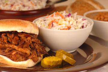 A pulled pork sandwich with cole slaw and beans