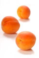 Three apricots on a white surface with a shallow depth of field