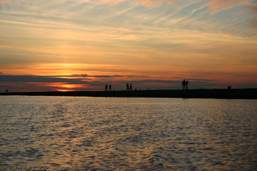Silhouettes of people on a pier on a background of a sunset