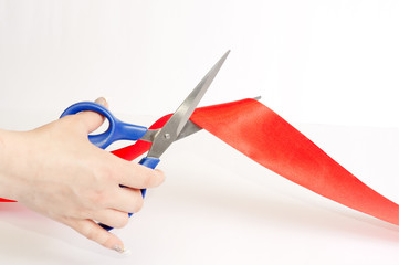 Scissors cutting a red tape