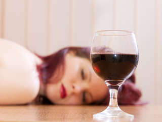 The girl laying on a table and a glass with wine