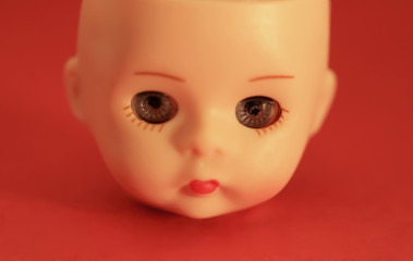 A close up of a doll's head on a red background