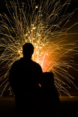 Father and daughter silhouetted while watching fireworks