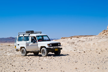 Jeep in the middle of lifeless desert - obrazy, fototapety, plakaty