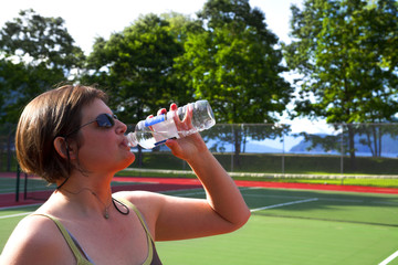 woman drinking water at a tennis court