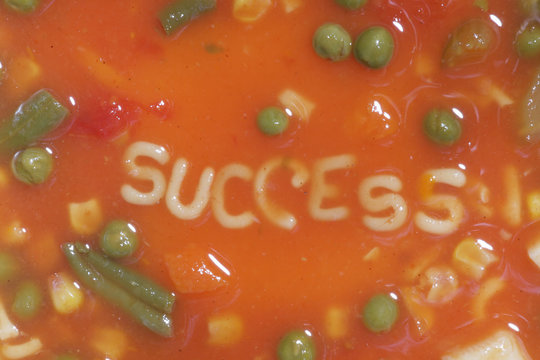 A bowl of alphabet soup with the word success in the middle