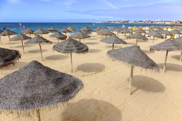 Beach scene with straw sunshades in a Summer day