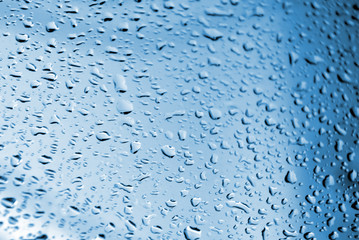 Blue background with raindrops on a windshield of a car