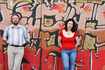 Woman and man against wall painted with graffiti