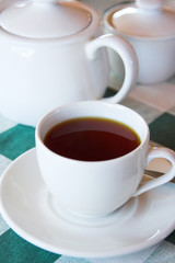 Cup of black tea on a green and white table cloth