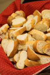 Cut slices of french loaf on a red cloth in a basket