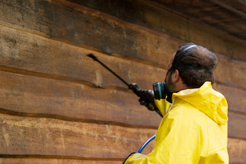 a man wearing a respiratore while he sprays some siding