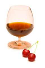 Glass of wine and two cherries on white