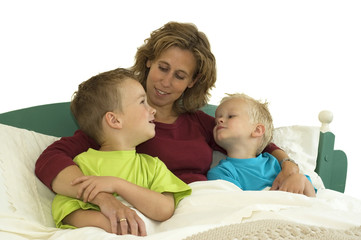 Mother and two sons lying happy in bed.