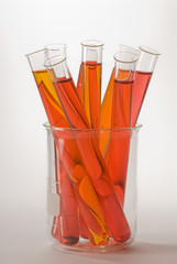 glass beaker and test tubes filled with orange and red liquids