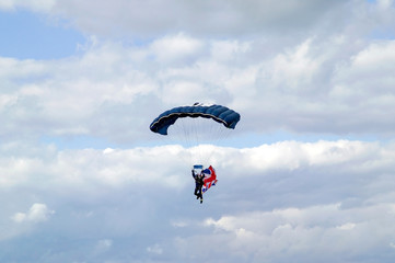 Parachutist with a Union Jack flag against a blue cloudy sky.
