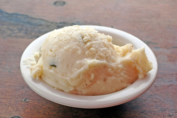 Bowl of seasoned mashed potatoes on table at restaurant.