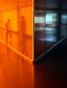 People reflected in angled orange corridor