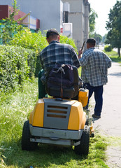 Fototapeta premium two men are cutting grass