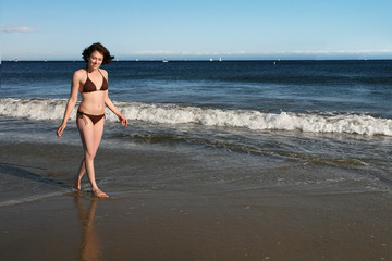 Fototapeta na wymiar A pretty woman walking on the beach near the water