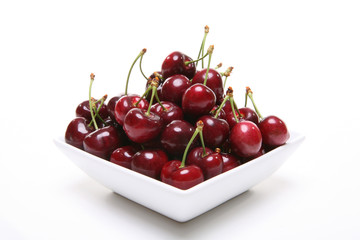 A filled bowl of cherries over white