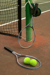Tennis court with balls and rackets in front of net