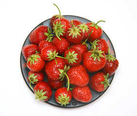Ripe red strawberry on a black plate.