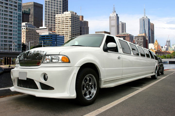 White classy limousine waterfront and skyscrapers - obrazy, fototapety, plakaty