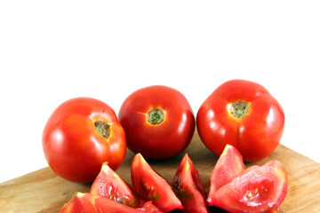 tomatos on a wooden plate cut in slices isolated on white