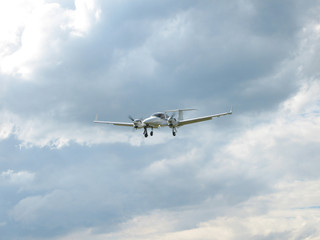 Fototapeta na wymiar weisses Sportflugzeug fliegt durch blauen und wolkigen Himmel