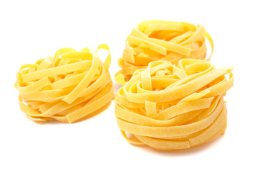 Three uncooked pasta nests with soft shadow on white background