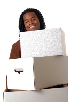 A smiling youg man carrying an armload of heavy boxes