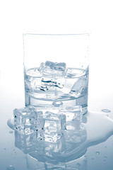 Glass of fresh mineral water reflected on wet background