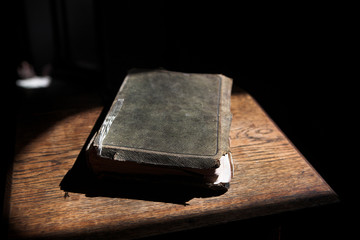 Leather covered old bible lying on a wooden table in a beam 