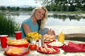 A beautiful blond wmasn sitting at a picnic table 