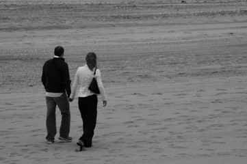 Fototapeta na wymiar jeune couple en promenade sur le sable - Tirage ilford HP5