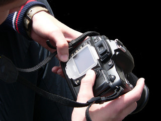 Black digital camera on hands photographer