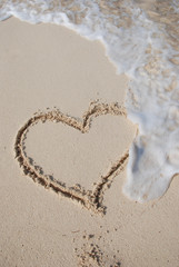 Heart on sand beach being washed away