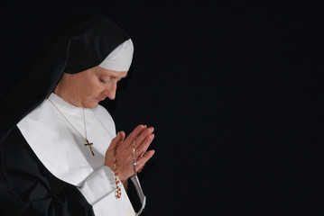 Middle aged devout nun in deep thoughts, praying. 