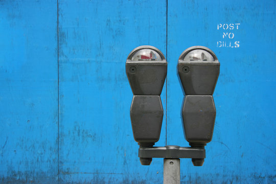 Two parkmeters over blue wooden panels