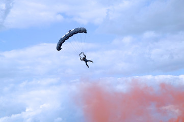 Parachutist coming into land through red smoke.