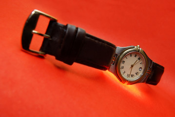 Silver watch with leather bracelet on a red background