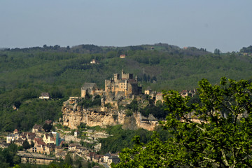 castle on side of rock with village below, france