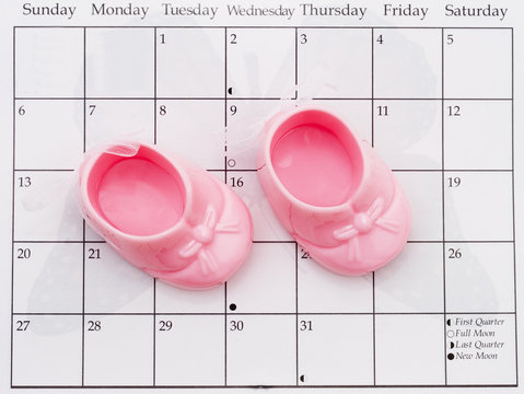 Two pink baby booties on a calendar