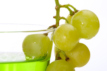 green colored liquor and bunch of grapes dipped into it