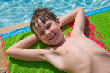 Young boy streched out, poolside
